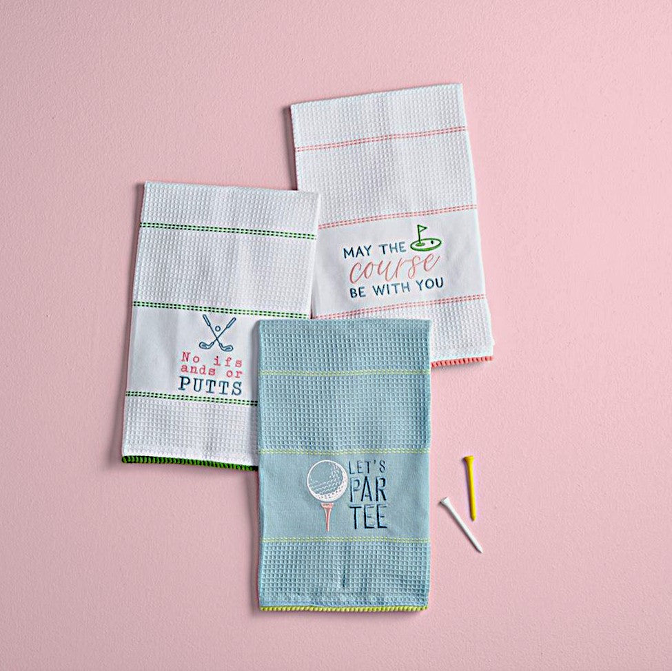 Three golf-themed kitchen towels laid out flat with embroidered waffle weave designs and golf-related sentiments and images.