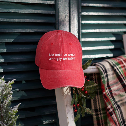 CJ Gift Goddess red washed cotton baseball cap with white embroidery reading "too cute to wear an ugly sweater".