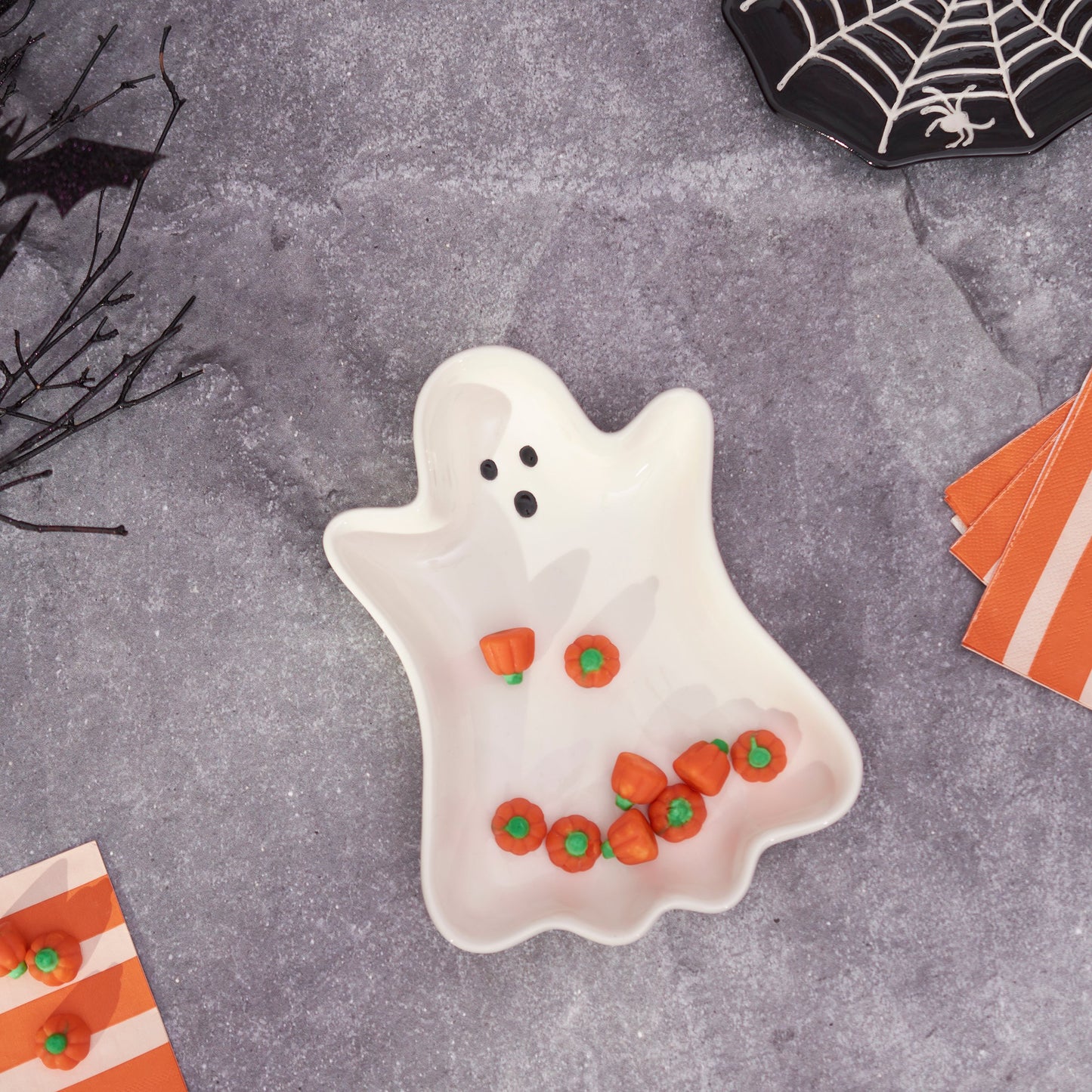Ghost-shaped plate with candy on a Halloween-themed table