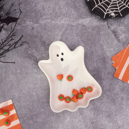 Ghost-shaped plate with candy on a Halloween-themed table