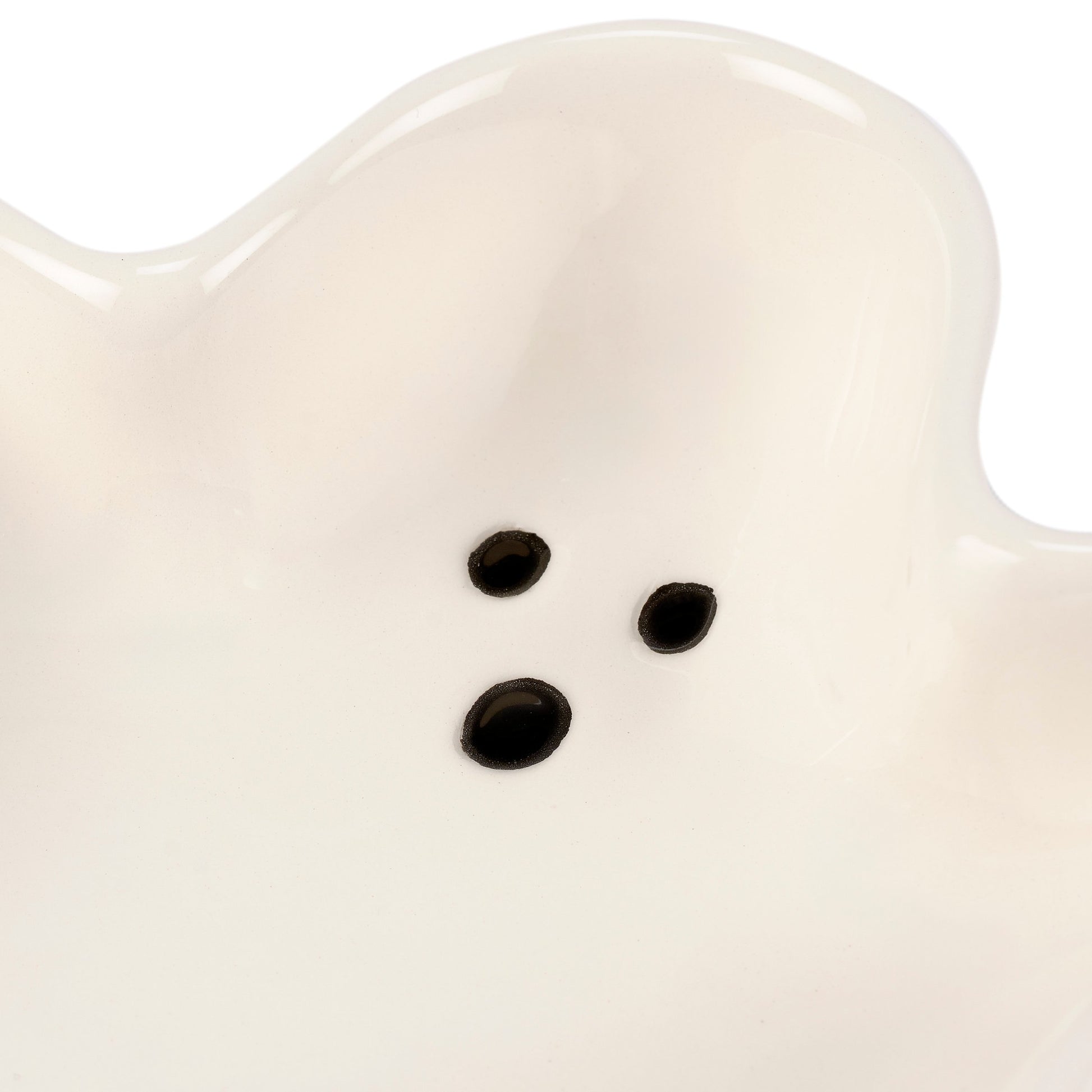 Close-up of a white ceramic ghost with black eyes on a white background
