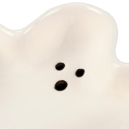 Close-up of a white ceramic ghost with black eyes on a white background