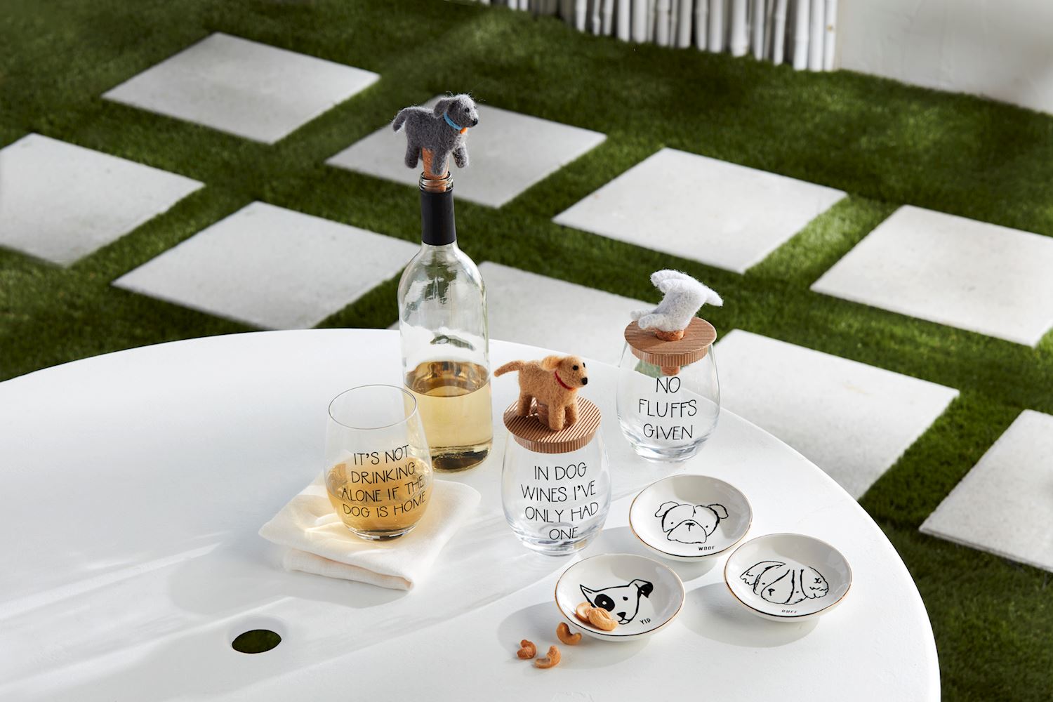Table with wine bottle, glasses, and decorative animal figures on a checkered floor.