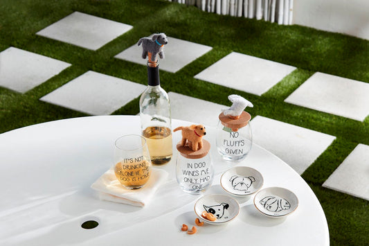 Table with wine bottle, glasses, and decorative animal figures on a checkered floor.