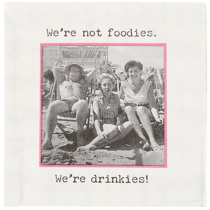 Vintage photo on a napkin of people at a beach with text 'We're not foodies. We're drinkies!' on a white background.