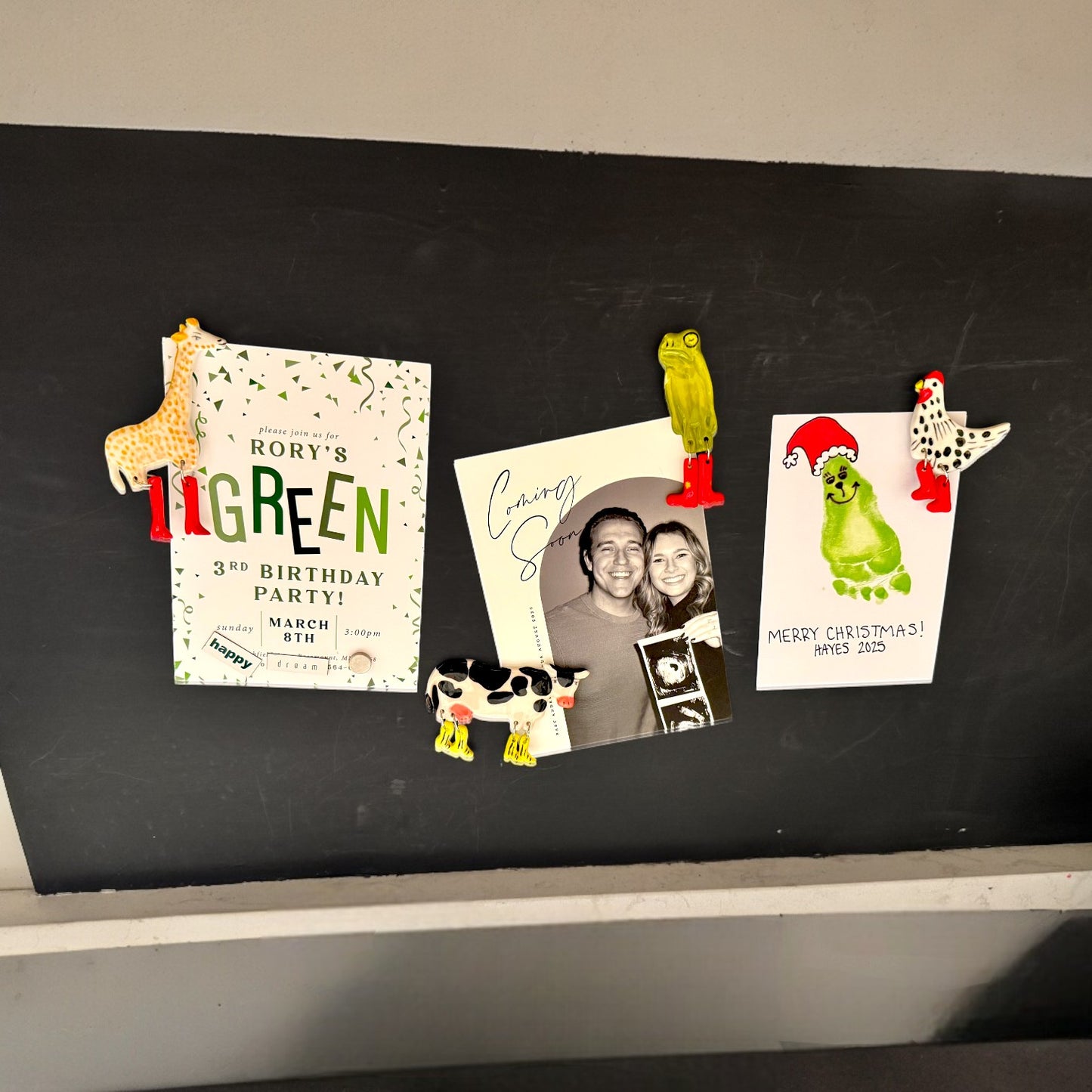 Decorative magnets on a blackboard with birthday invitations and a photo