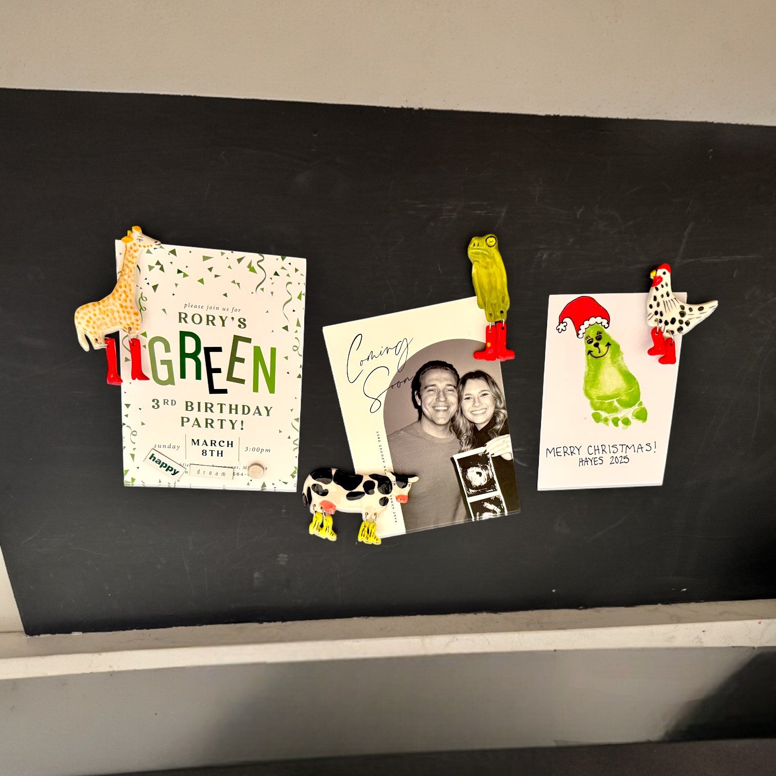 Decorative magnets on a blackboard with birthday invitations and a photo