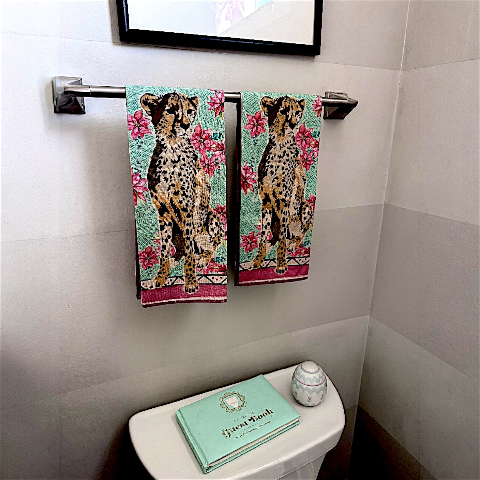 Bathroom with cheetah-themed towels hanging on a rack above a toilet.