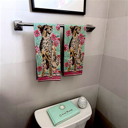 Bathroom with cheetah-themed towels hanging on a rack above a toilet.