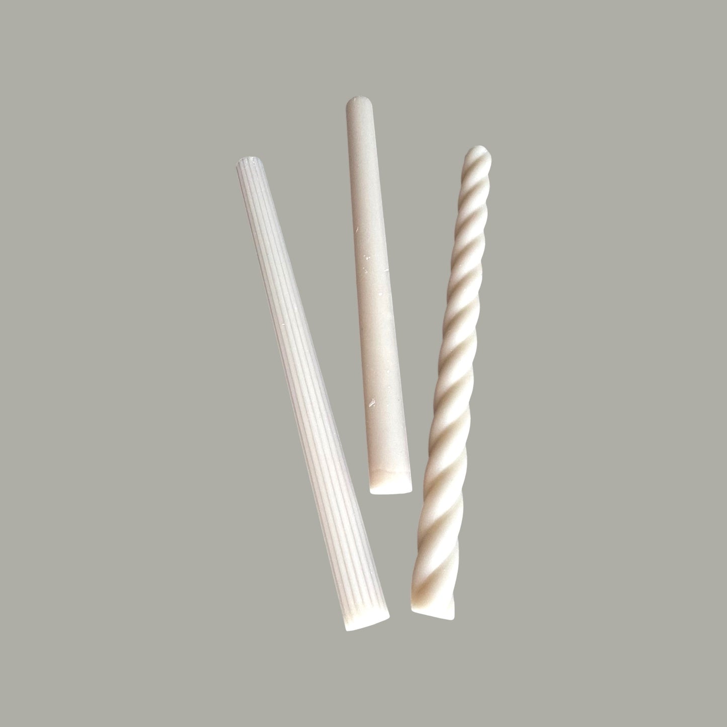 Three white decorative candles with different patterns 