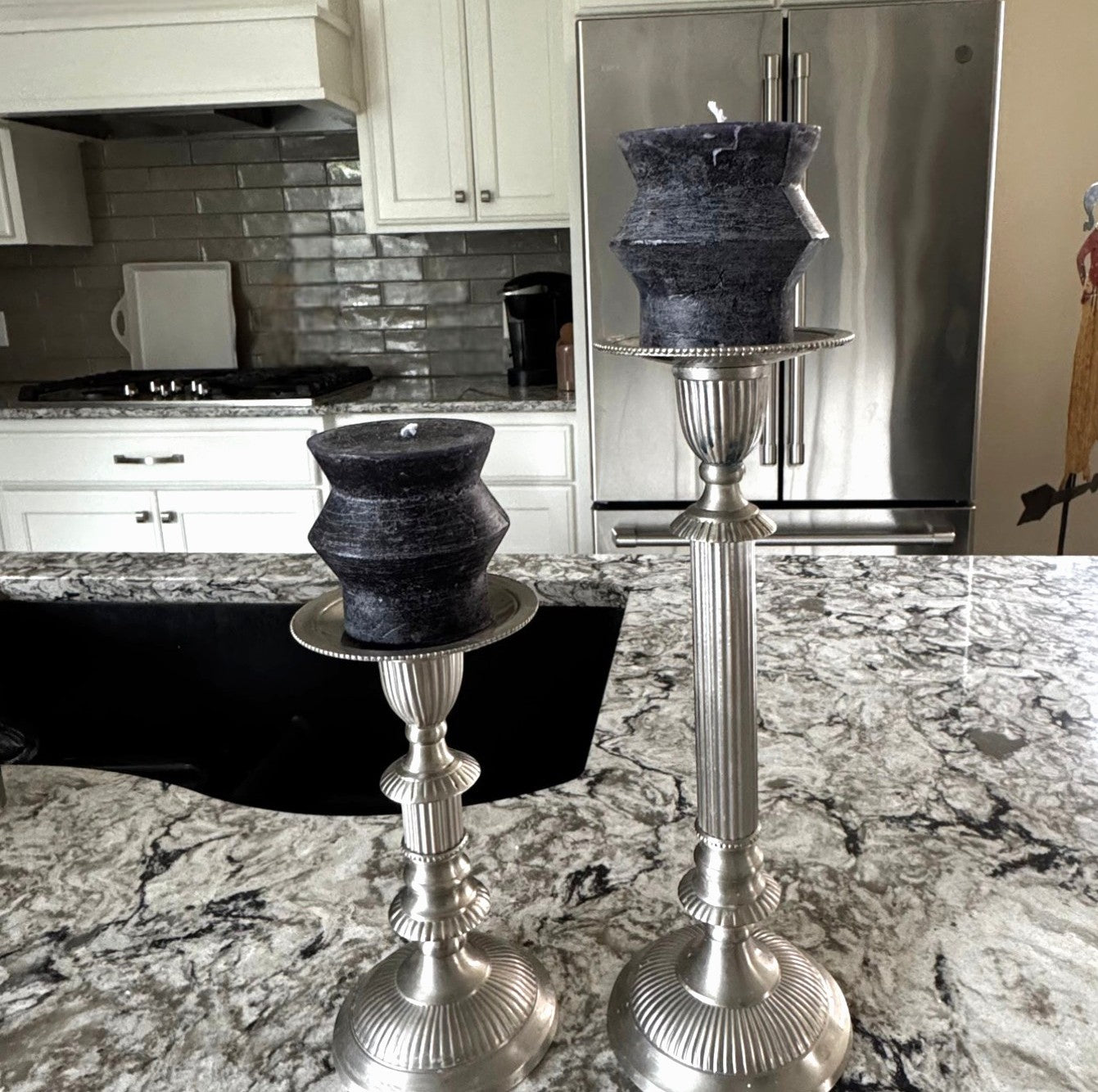 Decorative sculptured candles on a kitchen counter with a modern kitchen background.