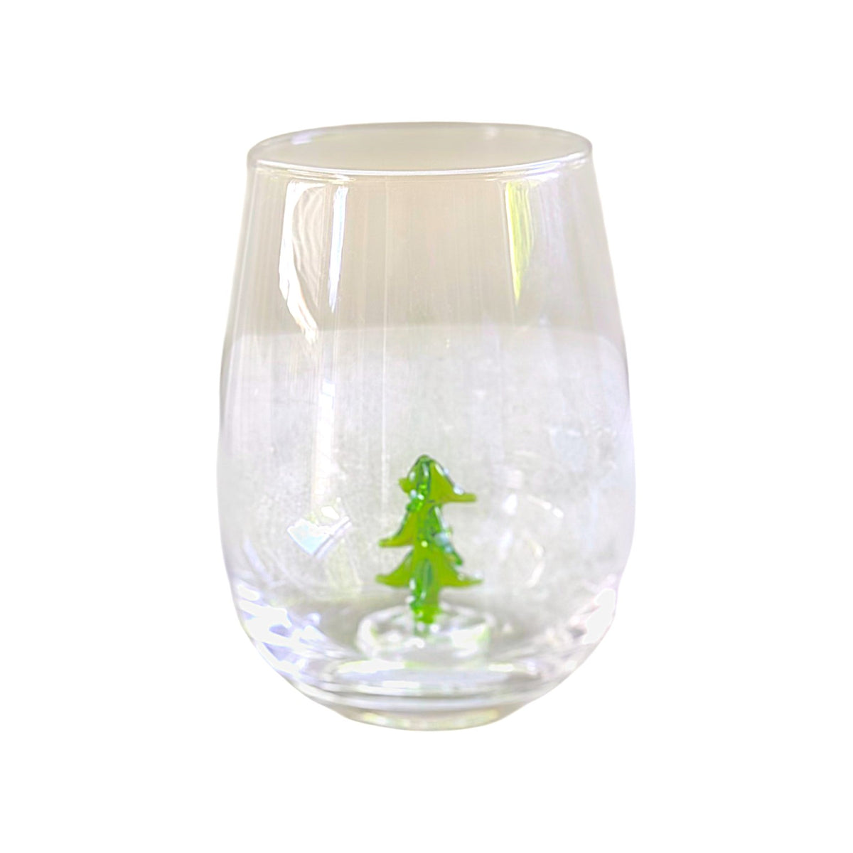 A clear stemless wine glass with a small green Christmas tree figure standing inside the base, shown against a plain white background.