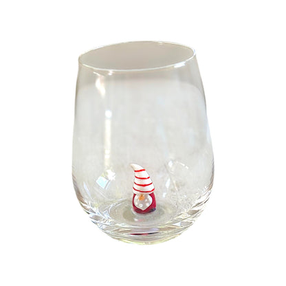 A clear stemless wine glass with a small red and white striped decorative figure inside the base, shown on a plain white background.