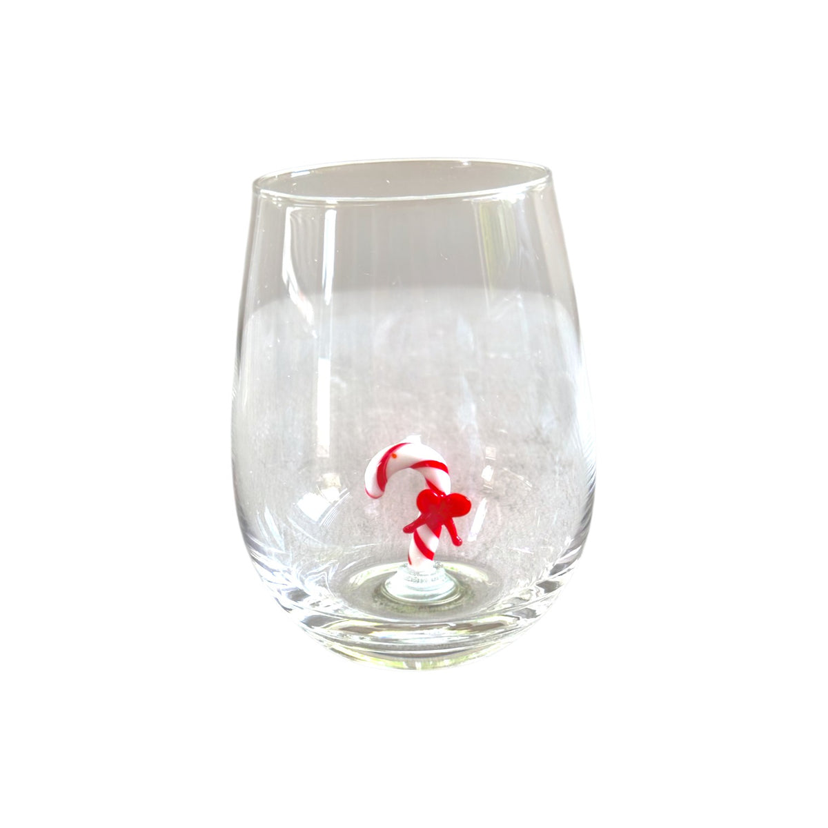 A clear stemless wine glass featuring a small red and white candy cane figure molded into the base, set against a plain white background.