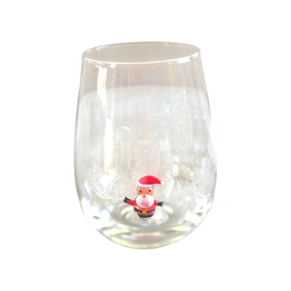 A clear stemless wine glass with a small Santa Claus figurine placed inside the base, shown against a plain white background.