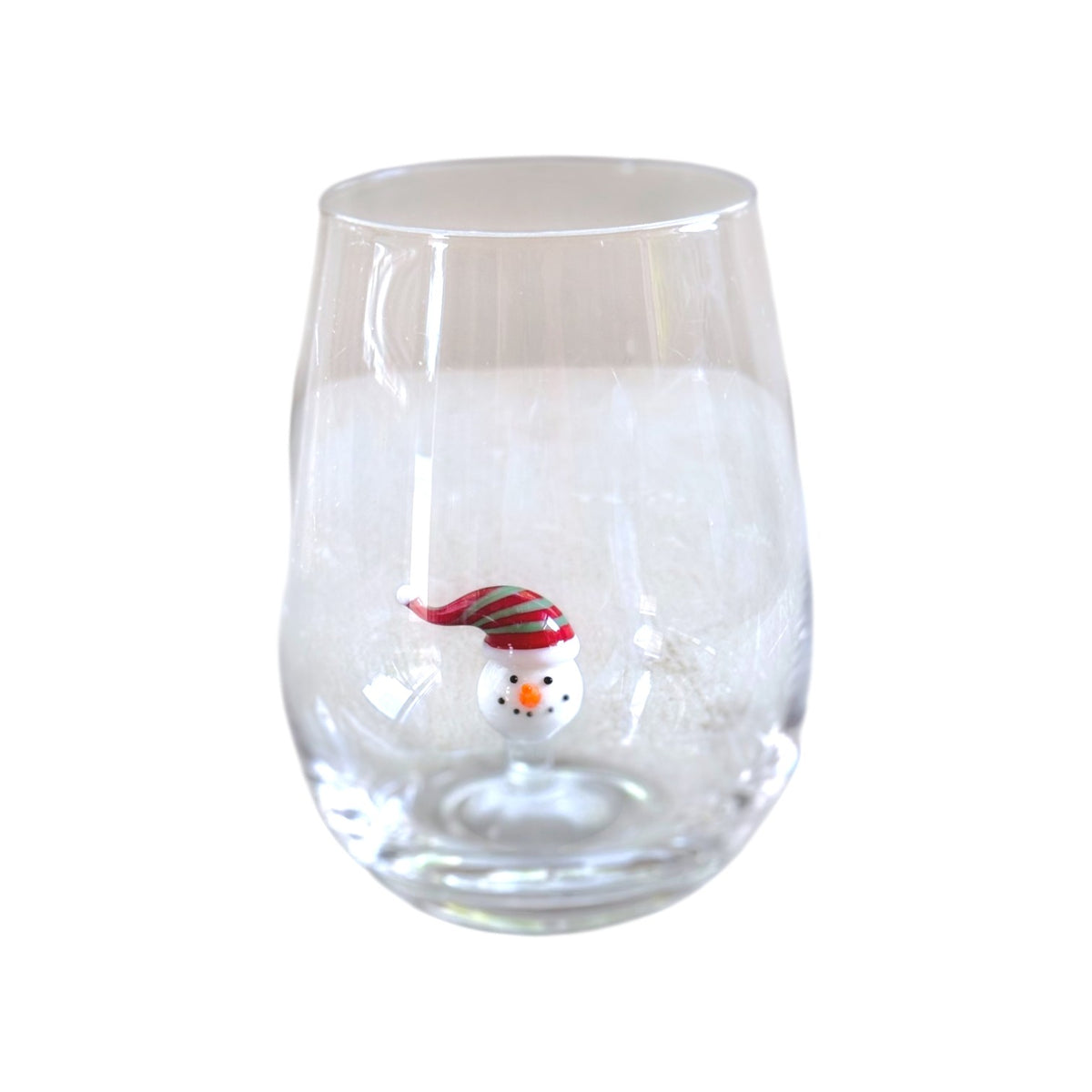 A clear stemless wine glass featuring a small snowman decoration wearing a red and green striped Santa hat near the bottom center.