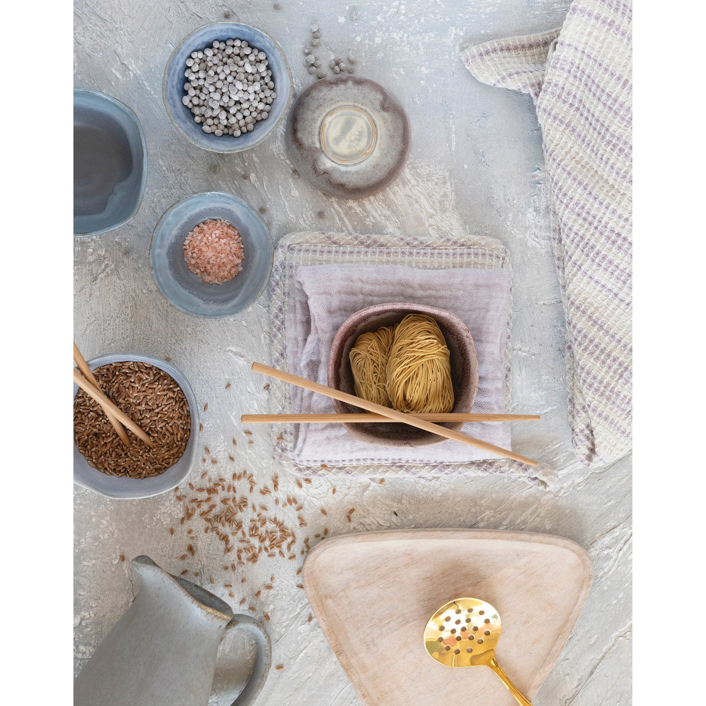 Knitting materials including yarn, needles, and small bowls on a textured surface.