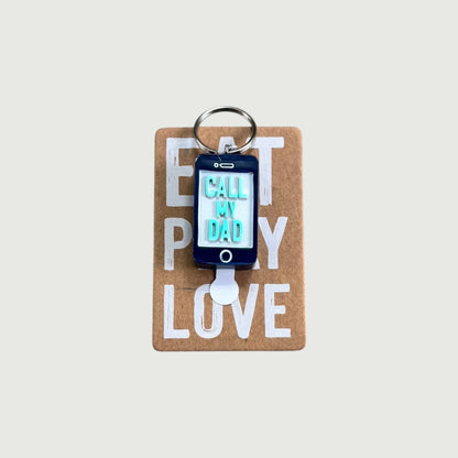 CJ Gift Goddess "Call My Dad" keychain shaped like a smartphone with blue and light blue lettering.