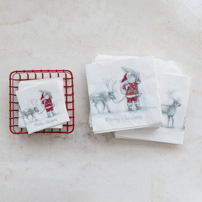 Set of Christmas-themed napkins with Santa and reindeer design on a white surface in a red holder